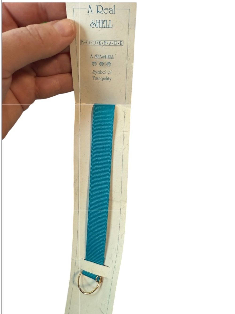 Real Shell" branded item featuring a teal-colored webbing strap